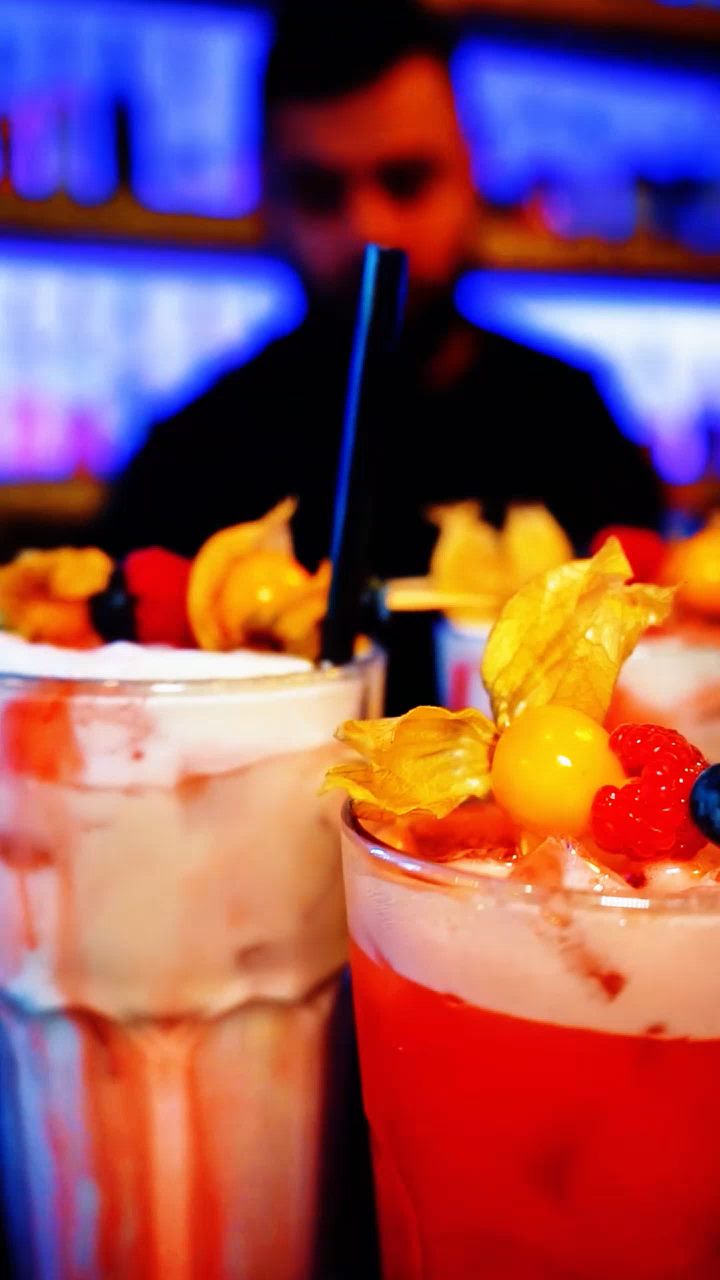 Zwei Cocktails mit Physalis und Beeren an der Bar